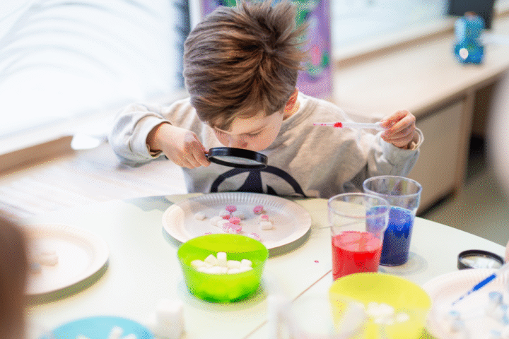 Kind experimentiert mit Lupe und Farben bei MINT-Experiment KiDE SCIENCE